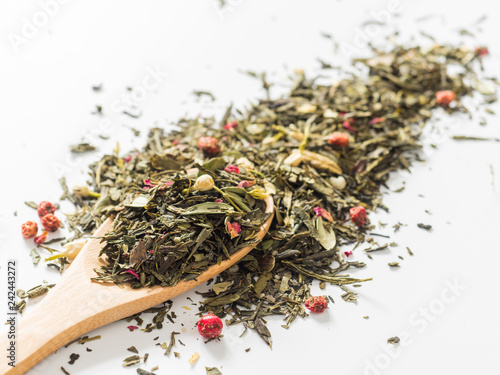 Dry leaves of Sencha green flower tea with cowberry leaf, red currant, Jasmine, rose petals, honey granules, forest berry aroma on white background