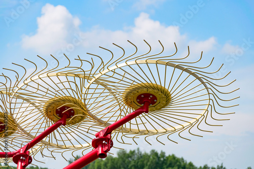 Side delivery rakes or Carted wheel rakes lifted off the ground against the blue sky. Rakes used for reducing drying time and keeping debris out of windrows for higher-quality bales.