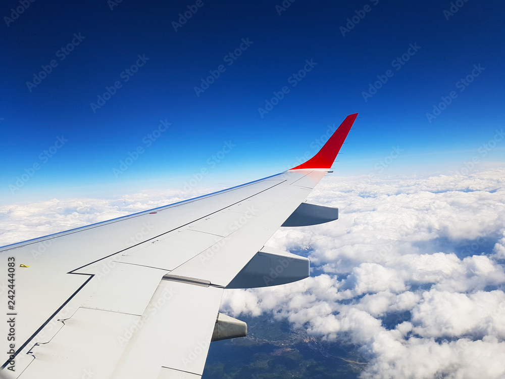 Obraz premium wing of an airplane flying above clouds