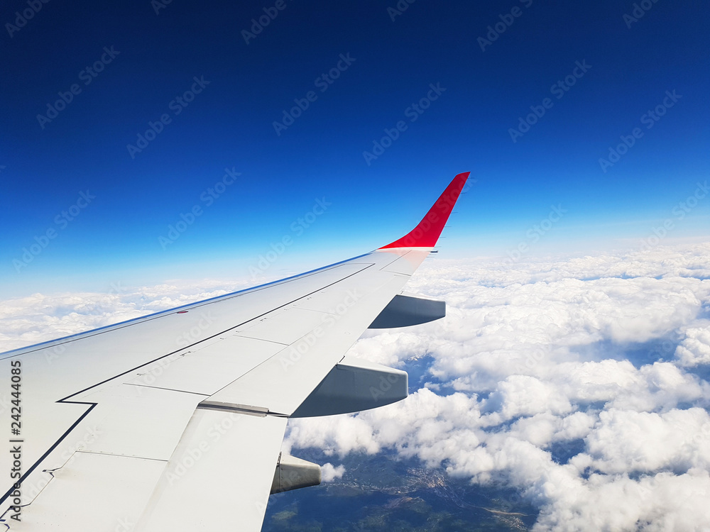 Fototapeta premium wing of an airplane flying above clouds