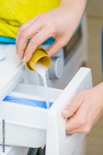 Person pouring fabric softener into washing machine