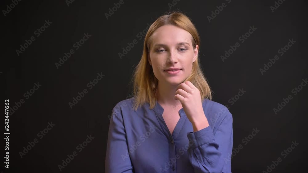 Portrait of formally-dressed woman flirting with camera and twisting her hair on black background. Portrait of formally-dressed woman flirting with camera and twisting her hair on black background.