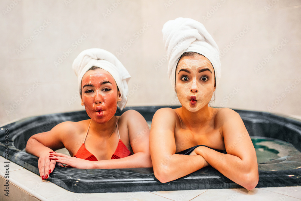 Amazed young women sit in jacuzzi and wonder. They look straight on