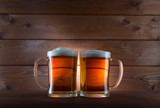 Two glasses of golden beer on wooden background