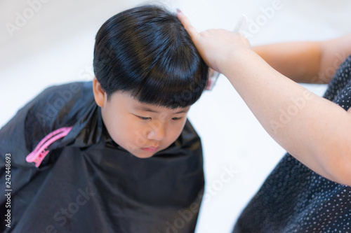 Grandmother is cutting hair of her grandson at home.