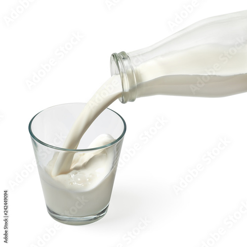 Fresh milk is poured from a bottle into a glass isolated on white background including clipping path