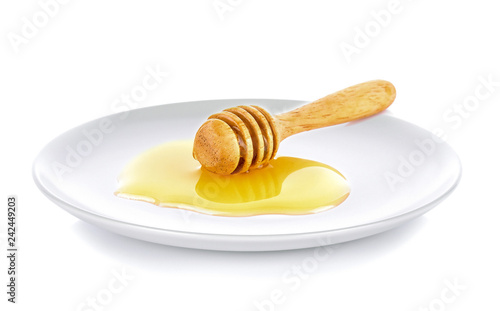 Wooden honey dipper with honey white plate on white background