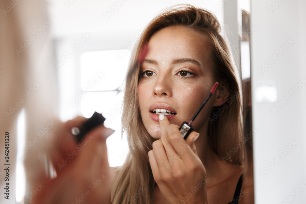 Young woman in lingerie underwear looking at mirror apply her lipstick lip  gloss doing makeup. Stock Photo | Adobe Stock