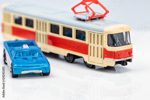 Toy red and yellow tram and toy blue car