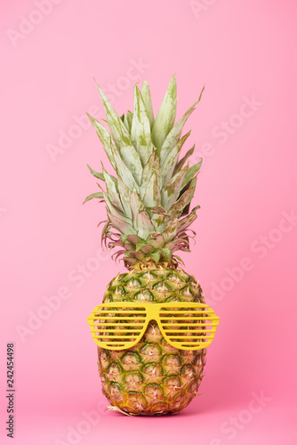 funny and tasty pineapple in sunglasses on pink background