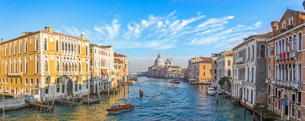 Grand Canal in Venice, Italy. Wide view of the main street panorama of the major street of Venice with motor boats with beautiful picturesque clouds in the sky. Basilica di Santa Maria della Salute.
