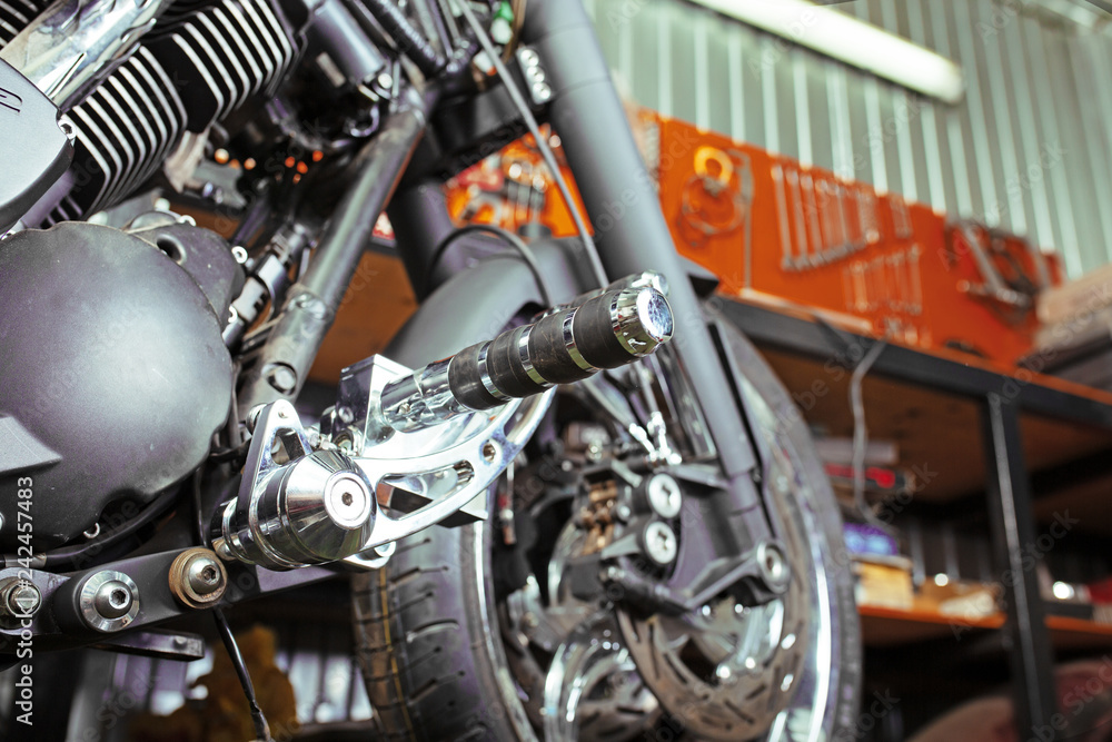 Cropped close up shot of beautiful and custom made motorcycle in the workshop Cropped close up shot of beautiful and custom made motorcycle in the workshop