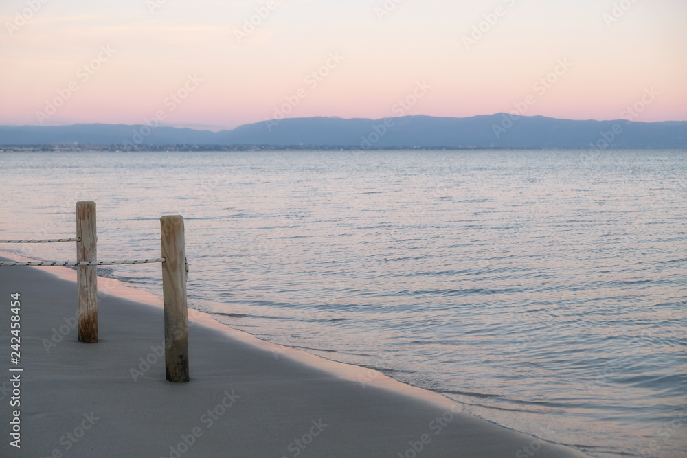 view of the Poetto beach at sunset with wooden pole and ropes - sella del diavolo calgiari.
