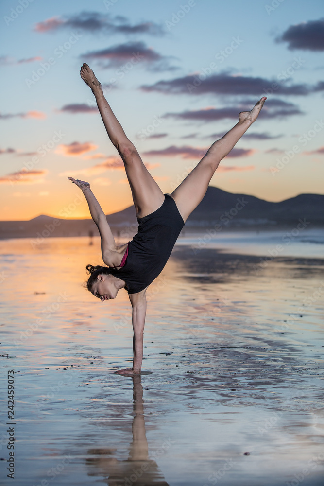 Slim woman training yoga on seashore