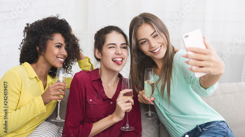 Young women taking selfie and drinking champagne