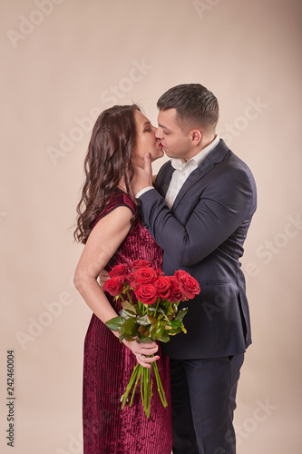 young married couple with a bouquet of red roses on a beige background on February 14 in Valentine's Day