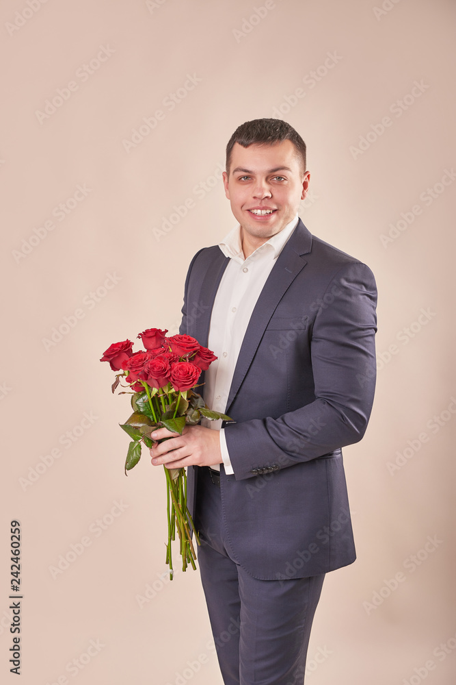 young attractive man with red roses on a beige background on Valentine's Day February 14 young attractive man with red roses on a beige background on Valentine's Day February 14