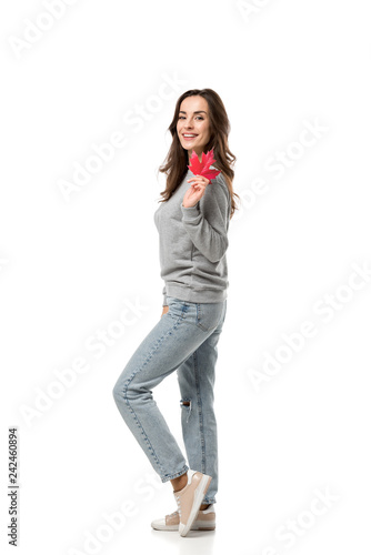 smiling woman in casual clothes holding maple leaf and looking at camera isolated on white