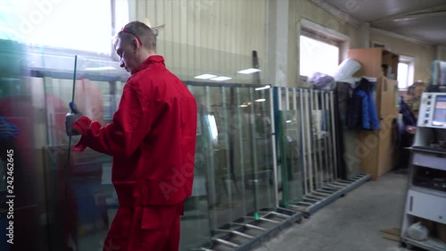 Manufacture of plastic windows and doors. Worker fastens the fittings with a screwdriver to the plastic window in the shop for the production of plastic and metal windows and doors. Screwing screws.
