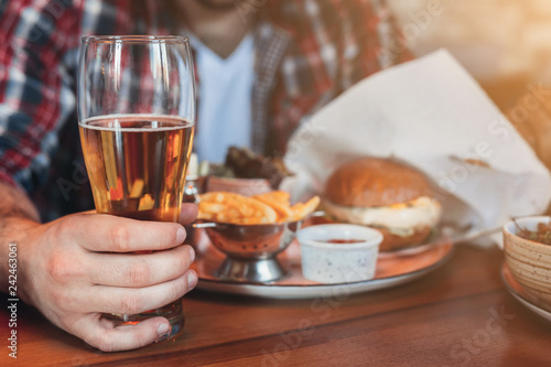 Man having rest, drinking beer and eating burger in pab