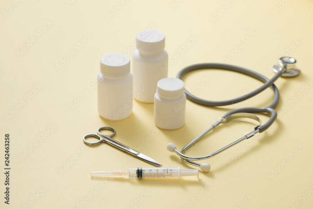 Composition set of medicine bottles and pills stethoscope on yellow background Composition set of medicine bottles and pills stethoscope on yellow background