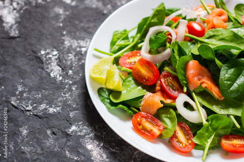 Selective focus Salmon Fresh green Salad with spinach, cherry tomatoes,baby spinach,  Concept for a tasty and healthy meal. Dark stone background. Top view. Close up. © lesterman