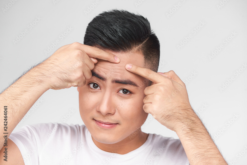 Close up photo of young man looking for acnes on his face Close up photo of young man looking for acnes on his face