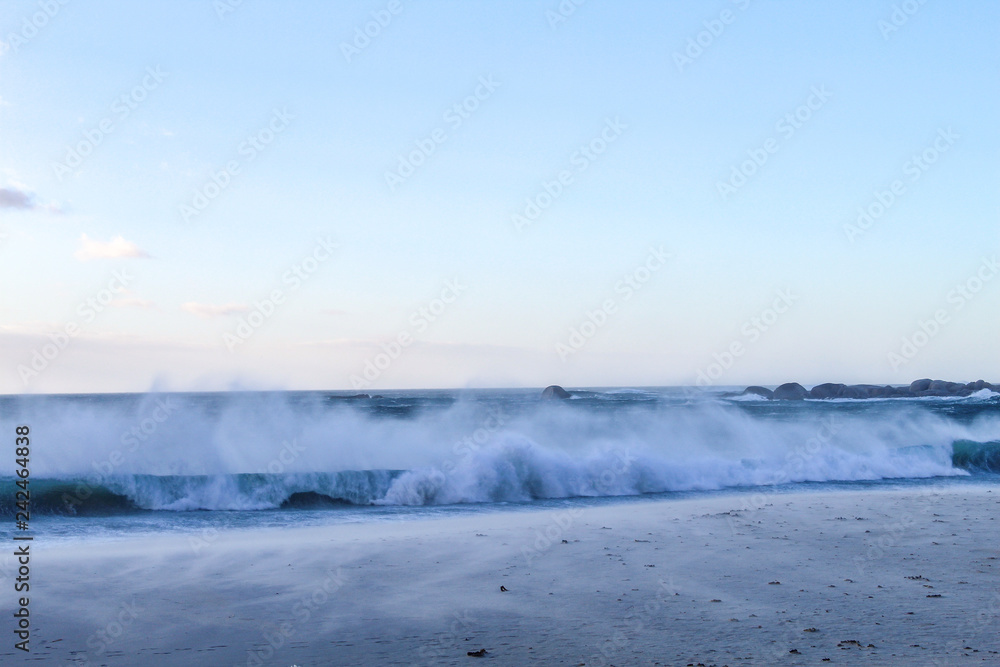Waves crashing on the beach on a summer evening at Camps bay in Cape Town, South Africa