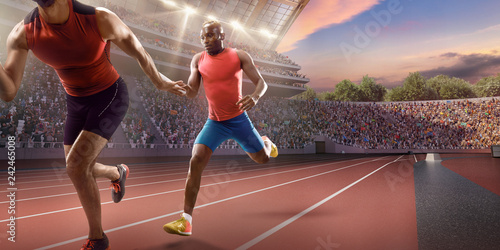Male athletes sprinting. Runner passes the baton at the running track in professional stadium