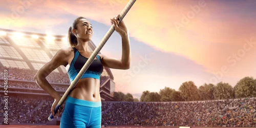 Fototapeta Młoda kobieta sportowiec skoku o tyczce z drążkiem. Kobiety w strojach sportowych na torze sportowym w profesjonalnym stadionie