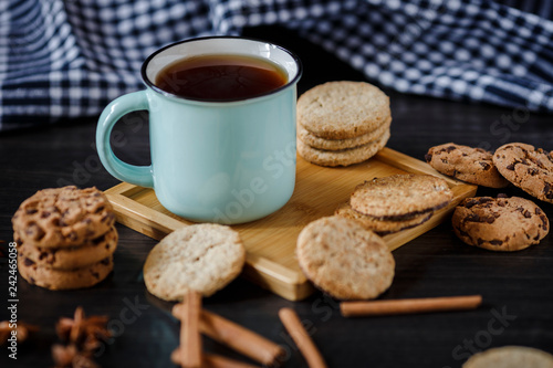 Cup of tea and various cookies on dark wooden background