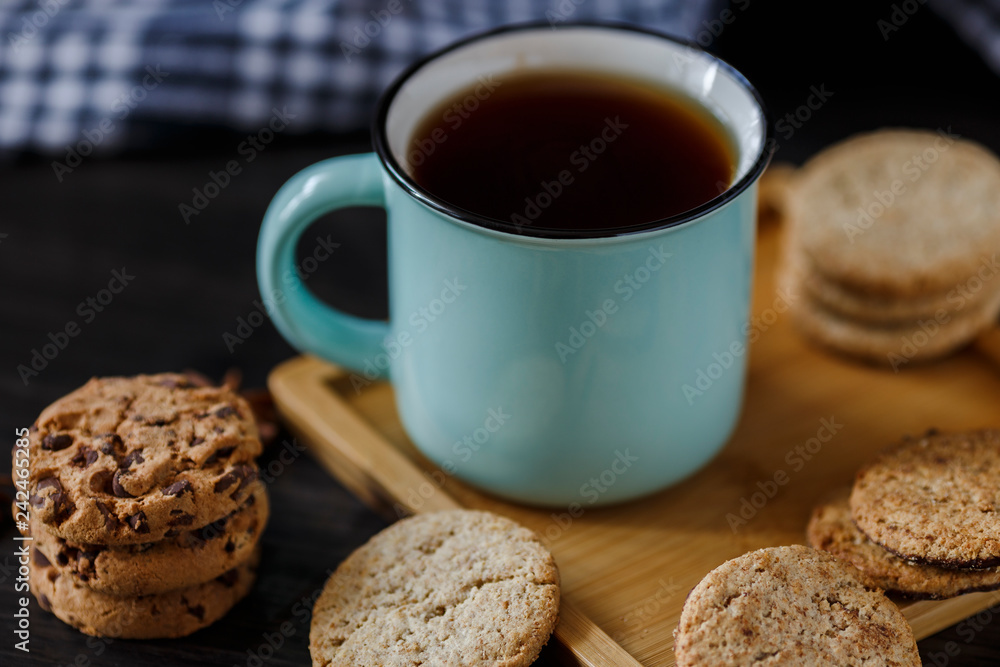 Cup of tea and various cookies on dark wooden background