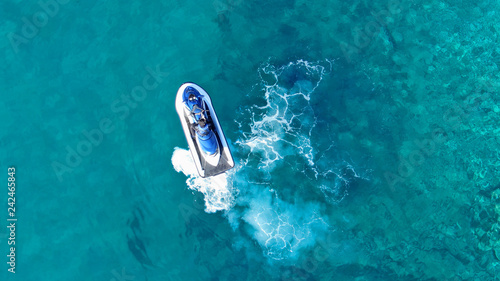 Aerial top view of jet-ski cruising in low speed in mediterranean emerald clear waters
