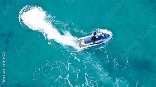 Aerial top view of jet ski cruising in low speed in mediterranean emerald clear waters