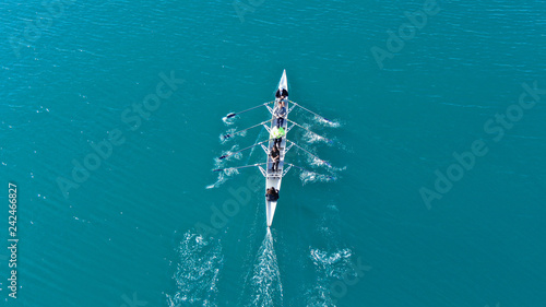 Aerial drone bird's eye view of sport canoe operated by team of young men in open sea