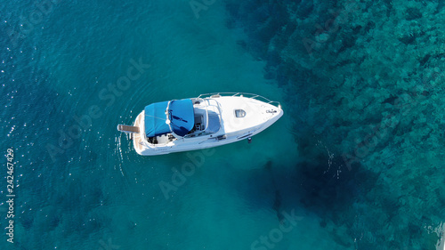 Aerial bird's eye view photo taken by drone of boat cruising in caribbean tropical beach with turquoise - sapphire waters
