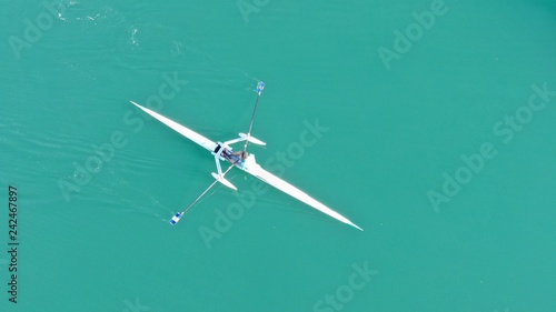 Aerial drone bird's eye view of sport canoe operated by young fit man in turquoise clear waters