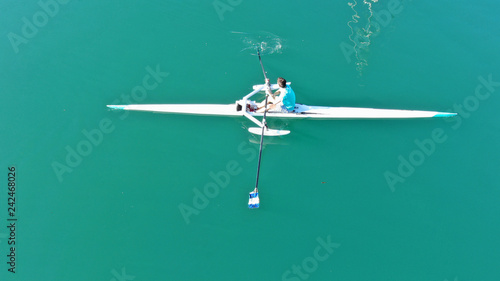 Aerial drone bird's eye view of sport canoe operated by young fit man in turquoise clear waters