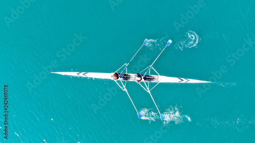 Aerial drone bird's eye view of sport canoe operated by young fit man in turquoise clear waters