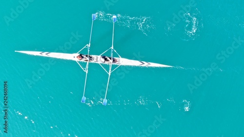 Aerial drone bird's eye view of sport canoe operated by young fit man in turquoise clear waters