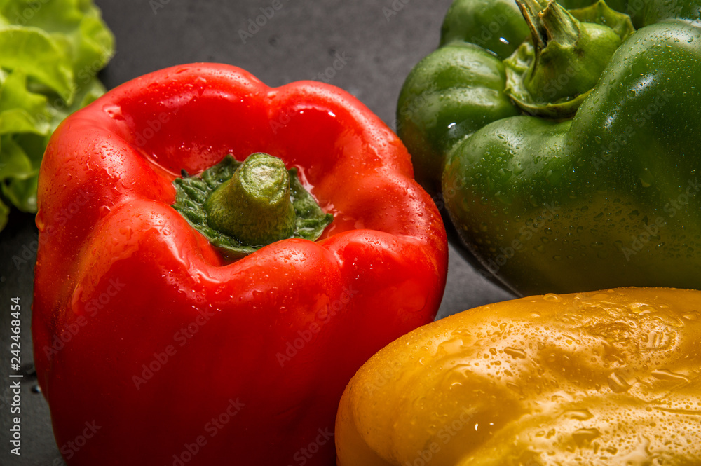 Close up, macro. Bright red, green and yellow fresh sweet pepper (paprika), covered with wet drops of water after washing. Black background. Close up, macro. Bright red, green and yellow fresh sweet pepper (paprika), covered with wet drops of water after washing. Black background.