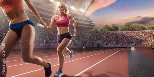 Female athletes sprinting. Runner passes the baton at the running track in professional stadium