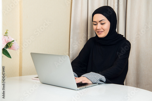 elegant attractive muslim woman using mobile laptop searching online shopping information in living room at home