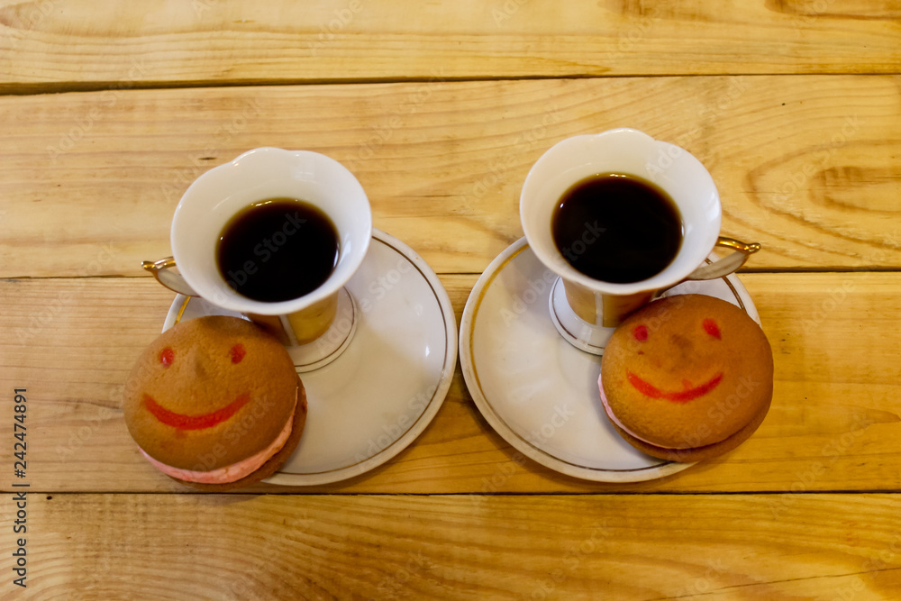 Fragrant coffee with a cake in the form of a smile in a plate on a wooden table Fragrant coffee with a cake in the form of a smile in a plate on a wooden table