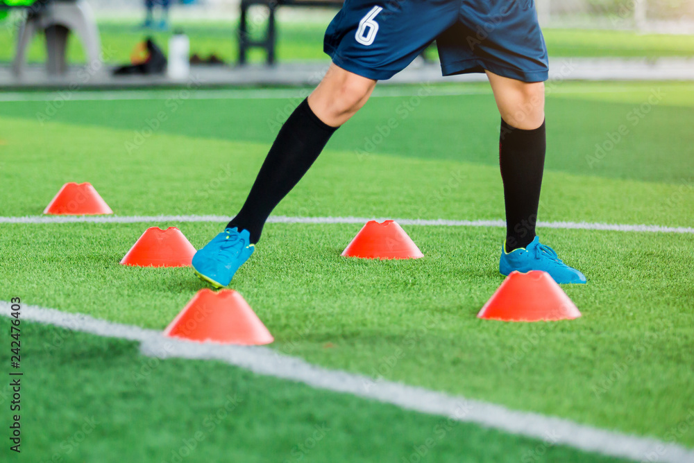 Obraz premium Soccer player Jogging and jump between cone markers on green artificial turf for soccer training