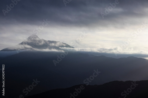 Foggy cloudscape on a mountain range landscape and grey sky © jordieasy