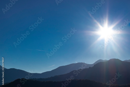 Sun shining on a solid blue sky mountain landscape photo