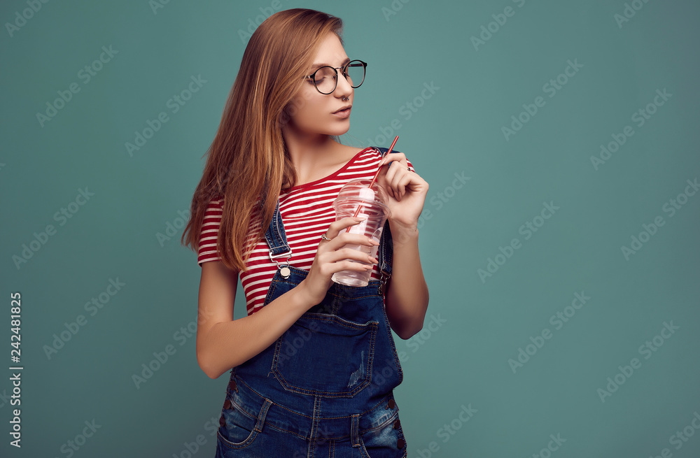 Cute teenage girl in denim overalls and glasses with soda water Stock Photo  | Adobe Stock