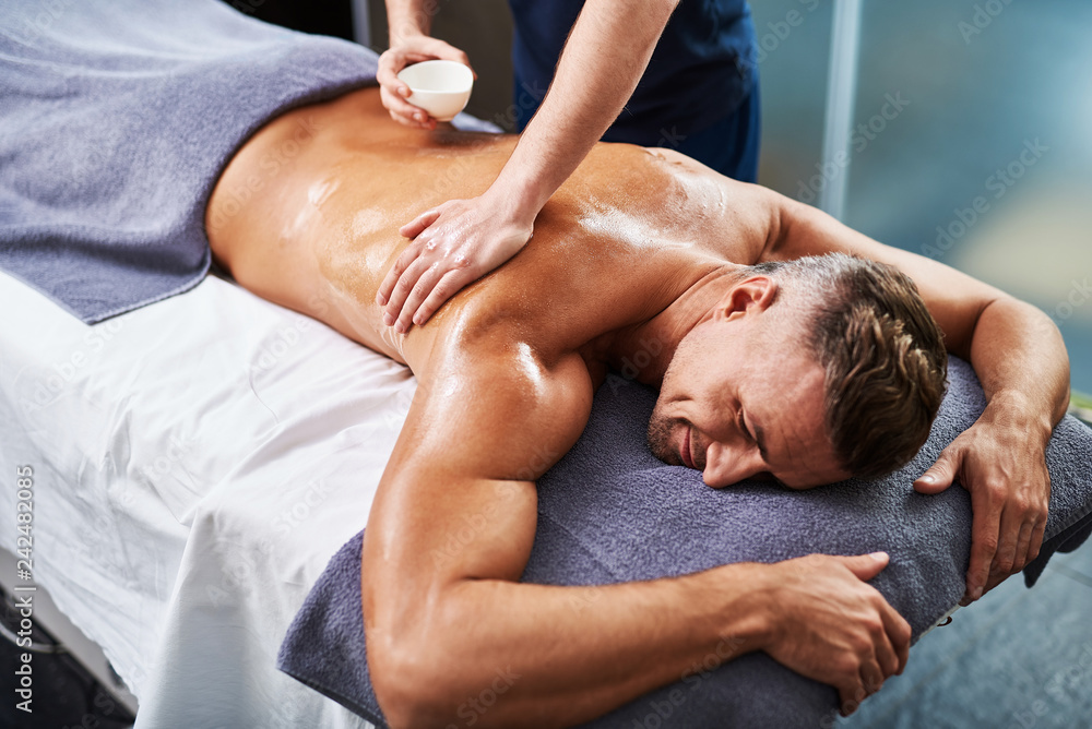 Fotografia do Stock: Masseur applying massage oil on man body | Adobe Stock