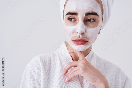 Canvas Print Upset girl with mask on her face standing against white background